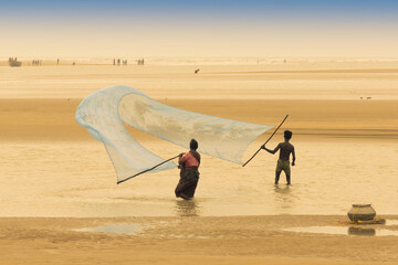 TAJPUR, WEST BENGAL, INDIA - JUNE 22ND, 2014 : A fisherman's wife and son catching fish with...