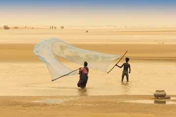 Foto op Canvas TAJPUR, WEST BENGAL, INDIA - JUNE 22ND, 2014 : A fisherman's wife and son catching fish with fishing net at seashore of Bay of Bengal in the morning. Fishing is livelihood for many people at Tajpur. © mitrarudra