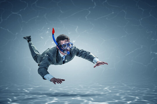 Young businessman in suit swimming