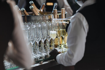 Waiter pouring champagne in stylish glasses at luxury reception, celebration.