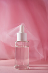 Transparent bottle of cosmetic gel on a pink background.