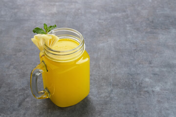 A glass of fresh pineapple juice with mint leaf and slice fruit. Cold Pressed Juice