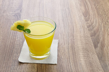 A glass of fresh pineapple juice with mint leaf and slice fruit. Cold Pressed Juice