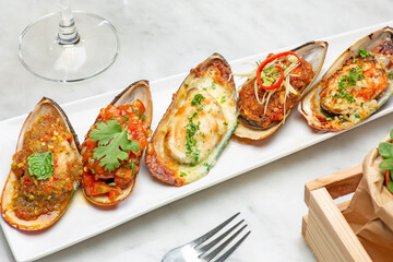 close-up of baked mussels with cheese on a plate and white background. 