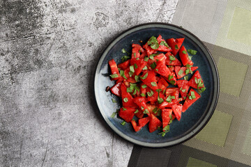 Tomato Salad on a round plate on a dark gray background. Top view, flat lay