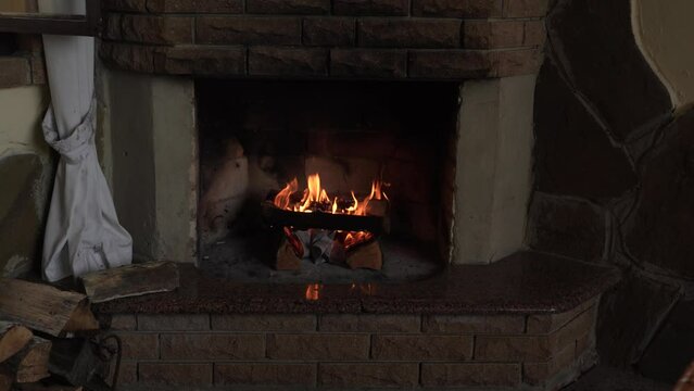 Burning firewood in fire-box of fireplace in country cottage. Rustic cooking oven with burning logs.