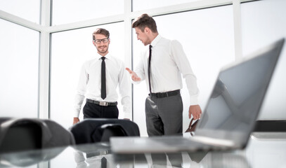 Two businessmen shaking hands standing at big window