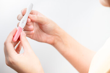  woman hand  holding pregnancy test. result female health problems and infertility. successful treatment IUI Intra – Uterine Insemination and ICSI. Pregnancy is not ready in adolescence..