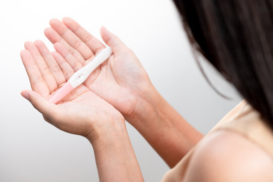  woman hand  holding pregnancy test. result female health problems and infertility. successful treatment IUI Intra &ndash; Uterine Insemination and ICSI. Pregnancy is not ready in adolescence..