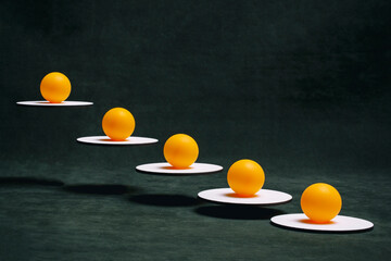 Still life with orange balls on white stands suspended in the air