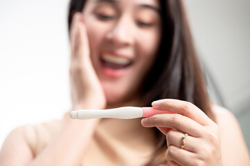 Asian woman holding pregnancy test feeling happy by positive result. female health problems and...