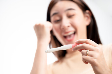 Obraz premium Asian woman holding pregnancy test feeling happy by positive result female health problems and infertility. successful treatment IUI Intra – Uterine Insemination and ICSI