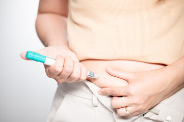 Woman making hormonal therapy injection into her belly. Close up syringe pen. Concept infertility. Treatment IUI Intra – Uterine Insemination and ICSI..