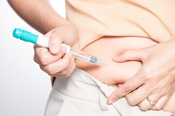 Woman making hormonal therapy injection into her belly. Close up syringe pen. Concept infertility. Treatment IUI Intra – Uterine Insemination and ICSI..