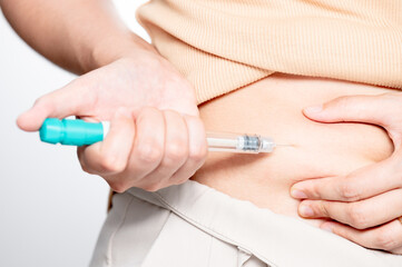 Obraz na płótnie Canvas Woman making hormonal therapy injection into her belly. Close up syringe pen. Concept infertility. Treatment IUI Intra – Uterine Insemination and ICSI..