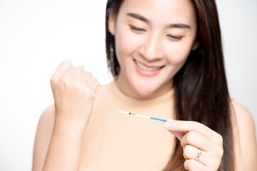 Happy asian woman shows a positive ovulation test. The concept of female fertility and high...
