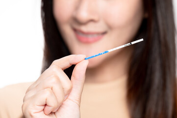 Happy asian woman shows a positive ovulation test. The concept of female fertility and high...