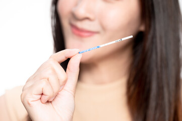 Happy asian woman shows a positive ovulation test. The concept of female fertility and high luteinizing hormone. The right time to conceive a child. infertility Concept.