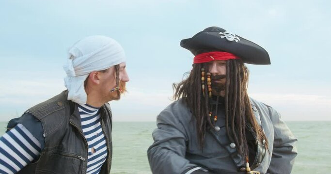 Dashing captain in a wig with dreadlocks decorated with beads and in cocked hat. He commands and gives tasks to his crew of pirates, actively gesticulating with hands, front view