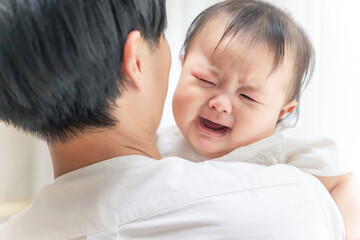 泣いている赤ちゃんを抱っこする男性
