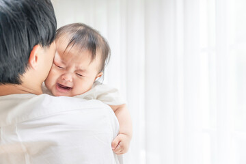 Obraz na płótnie Canvas 泣いている赤ちゃんを抱っこする男性