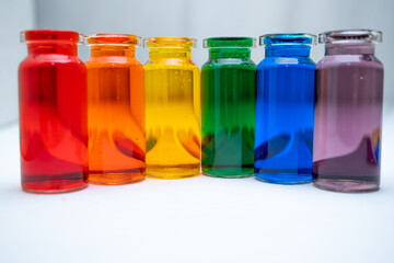 hilera de botellitas con agua coloreada multicolor, arcoiris con fondo blanco