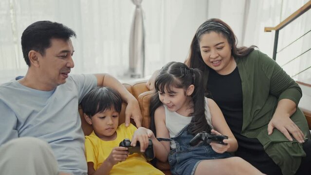 Happy family adult parents with cute kids relax on sofa playing video game having fun with together.