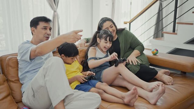 Happy family adult parents with cute kids relax on sofa playing video game having fun with together.
