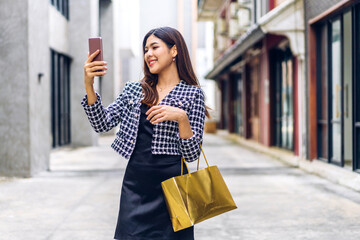 Portrait of smiling beauty asian fashion happy woman relax and enjoy shopping time summer sale walk and holding shopping colorful bag to buy something purchases use smartphone at store