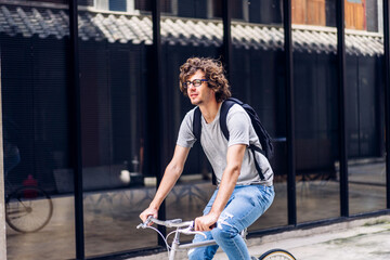 Fototapeta na wymiar Portrait of casual hipster handsome businessman with backpack looking forward while commuting riding bicycle on the street city way go to work.business travel transport bike concept