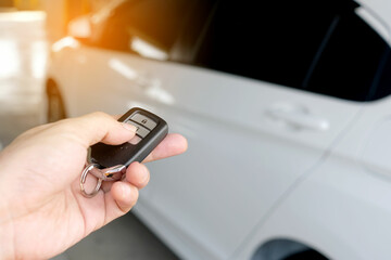 The man in the hand held the remote control of the car, he opened the remote control of the car door. To drive a car