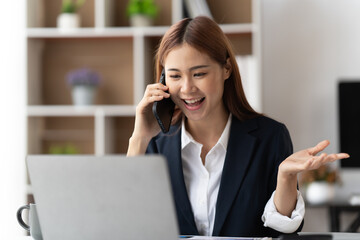 Asian businesswoman in formal suit in office happy and cheerful during using smartphone and working, copy space.