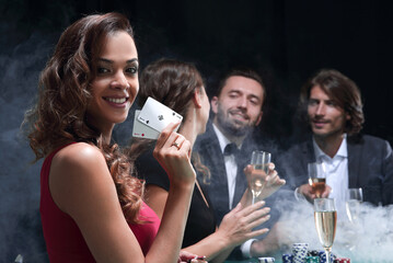 young brunette woman playing poker on black background