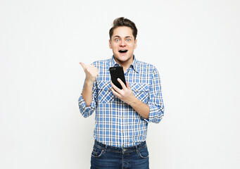 Portrait of a shocked young man wearing blue shirt looking at mobile phone