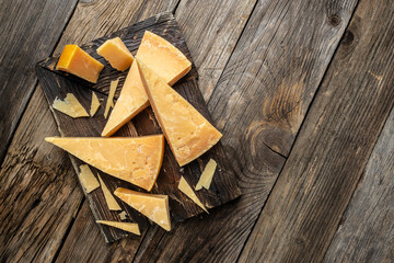 Parmesan cheese on a wooden board, Hard cheese on a dark background. banner, menu, recipe place for text, top view