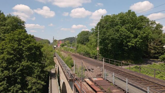 Freight train heading off into the distance viewed from a rusty old train trestle. Wide angle slow zoom on a sunny day in Germany
