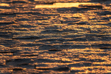 Stone block pavement in the rays of the setting sun. Texture