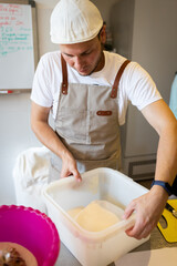 The process of making wheat bread in an artisan bakery. The folding of the dough during fermentation. Vertical photo.