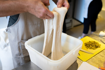 The process of making wheat bread in an artisan bakery. The folding of the dough during fermentation. Front view.