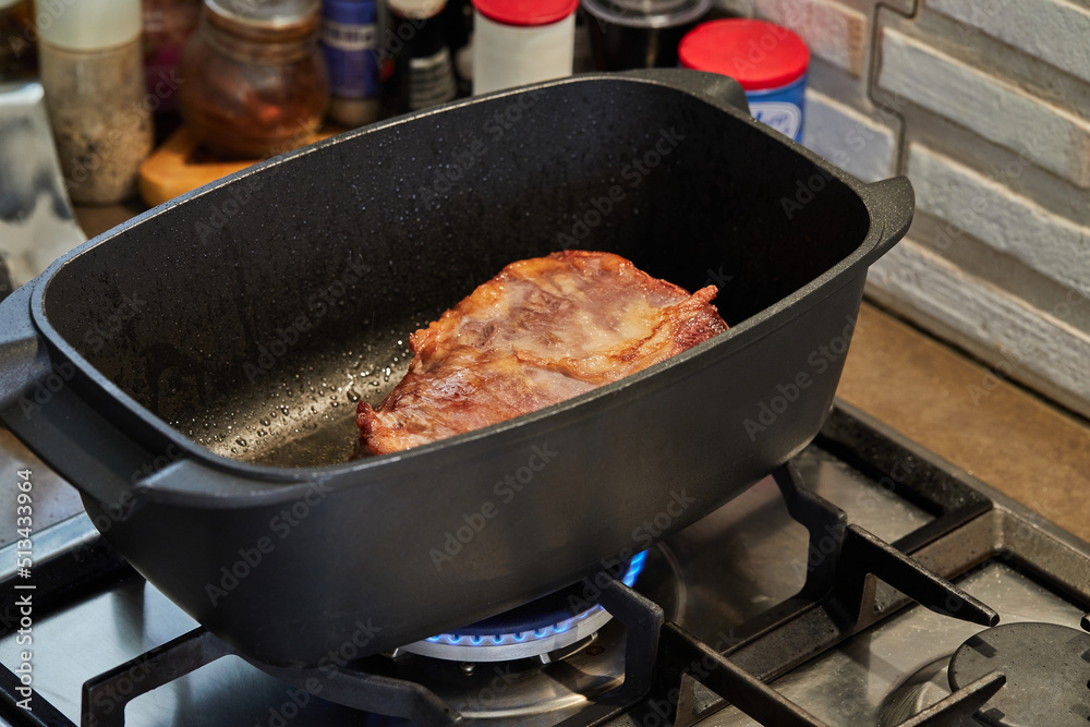 Poster Piece of meat is roasted in rectangular pot for cooking over fire on gas stove