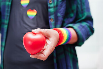 Asian woman holding red hert with rainbow flag, LGBT symbol rights and gender equality, LGBT Pride Month in June.