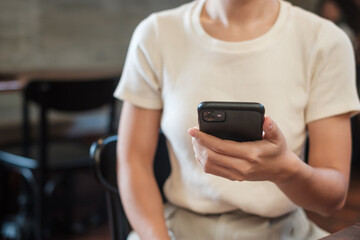 Casual Businesswoman holding and using smartphone for sms messages, young woman typing touchscreen mobile phone in cafe or modern office. lifestyle, technology, Social media and network concept