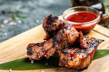 Delicious barbecued ribs seasoned with a spicy sauce and served on wooden board, Food recipe background. Close up