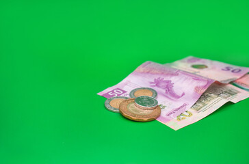 Billetes de pesos mexicanos con monedas en un fondo verde de economia 