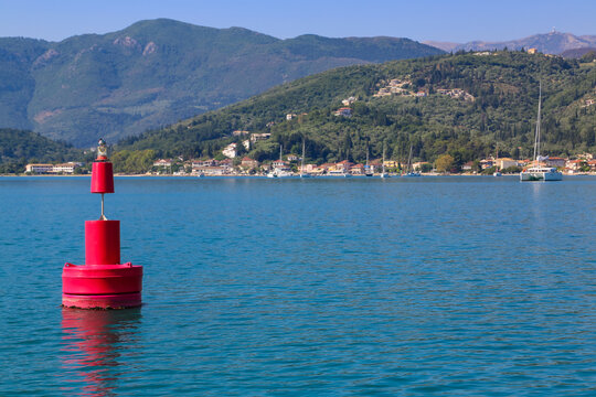 Bird sitting on red port buoy in Greece.