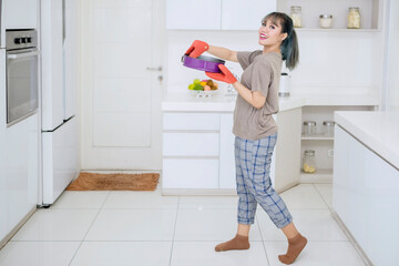 Happy woman holding a baking tray in the kitchen