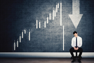 Sad businessman sit with declining finance chart