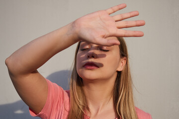 woman closes her hand from bright sunlight, a shadow on her face. The concept of conflict, mental health, depression