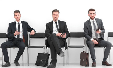 group of business people with smartphones sitting in the office hallway