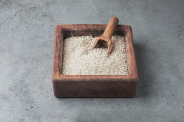 dry white rice in a wooden bowl on a gray background
